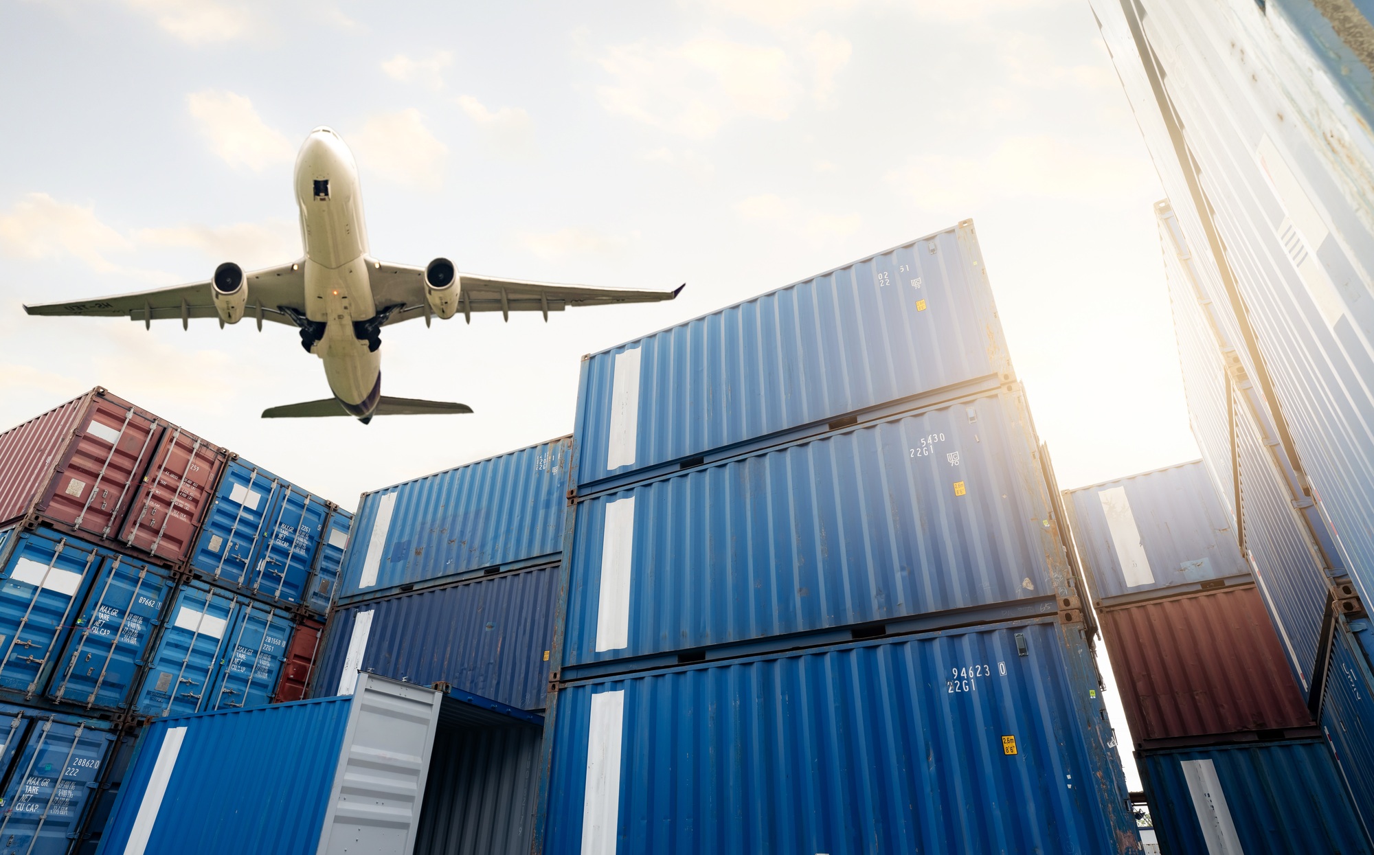 Air logistics. Cargo airplane flying above stack of logistic container. Cargo and shipping business.